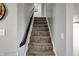 Carpeted stairway leading to the upper level with a dark wood handrail, enhancing the home's classic design at 5311 Larita Ln, Anderson, IN 46017
