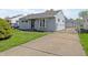 View of a gray home with a well maintained lawn, fenced driveway, and manicured landscaping at 5427 E 19Th St, Indianapolis, IN 46218