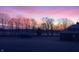 Charming outbuildings stand serenely, with a frosty field adding a touch of winter's magic, set against a breathtaking sunset at 5679 S 675 W, New Palestine, IN 46163