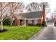 Beautifully maintained home with brick facade, mature trees, and a detached garage accessible by a paved driveway at 6041 Garver Rd, Indianapolis, IN 46208