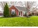 Quaint brick home with a well-kept lawn, decorative shutters, and mature landscaping at 6041 Garver Rd, Indianapolis, IN 46208