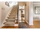 Hallway with hardwood floors, carpeted stairs, and a glimpse into a bright, modern kitchen at 6041 Garver Rd, Indianapolis, IN 46208