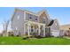 Two-story home featuring a welcoming front porch, stone accents, gray siding and lush lawn at 6557 Eagles Nest Ln, McCordsville, IN 46055