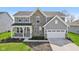 Charming two-story home with stone accents, gray siding, covered porch, manicured lawn, and a two-car garage at 6557 Eagles Nest Ln, McCordsville, IN 46055