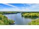 Expansive aerial view of a serene lake surrounded by lush, dense forest and a clear blue sky with wispy clouds at 7809 S Solitude Ln, Trafalgar, IN 46181