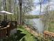 Wooden deck overlooking lake with table, chairs, and umbrella, surrounded by trees at 7809 S Solitude Ln, Trafalgar, IN 46181