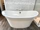 Close up of a large white soaking tub and stylish wood-look floor in a luxurious bathroom at 7809 S Solitude Ln, Trafalgar, IN 46181