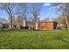 Exterior shot of the red brick home showcasing a large backyard and mature trees at 8017 Wallingwood Dr, Indianapolis, IN 46256