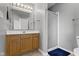 Neutral bathroom featuring a light wood vanity, a large mirror with Hollywood lighting, and a glass-doored shower at 9442 Avon Strand # D, Avon, IN 46123