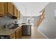 Open kitchen featuring wood cabinets, granite counters, stainless steel dishwasher, and staircase access at 9442 Avon Strand # D, Avon, IN 46123