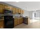 Spacious kitchen with wood cabinets, black appliances, and access to a patio at 9442 Avon Strand # D, Avon, IN 46123