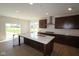 Open kitchen featuring an island with sink, quartz countertops, and dark wood cabinetry at 10543 Banyan Wood Ct, Indianapolis, IN 46239