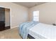 Bedroom features a bed, neutral walls, carpet, and a window; the open doorway leads to wood floors at 12926 University Cres # 2C, Carmel, IN 46032