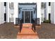 Inviting building entrance features red brick steps, a black door, and blue accents at 12926 University Cres # 2C, Carmel, IN 46032