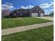 Charming brick home features a two-car garage, manicured lawn, and a blooming tree at 1513 Tottenham Dr, Danville, IN 46122