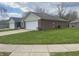 Exterior view of home featuring a two-car garage, brick accents, and a well-manicured lawn at 1623 Senior Ct, Shelbyville, IN 46176
