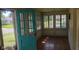 Cozy sunroom with hardwood floors and a turquoise door leading to the outside at 213 S Brittain Ave, Muncie, IN 47303