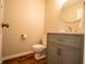 Stylish half-bathroom with grey vanity, marble countertop, gold fixtures, and round mirror at 2328 Discovery Dr, Anderson, IN 46017