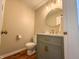 Stylish half-bathroom with grey vanity, marble countertop, gold fixtures, and round mirror at 2328 Discovery Dr, Anderson, IN 46017