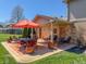 Brick patio with an orange umbrella, multiple chairs, a brick exterior and well manicured landscaping at 2328 Discovery Dr, Anderson, IN 46017