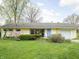 Single-story house featuring manicured front lawn and garden with mature trees and a colorful blue front door at 2816 Canterbury Ln, Indianapolis, IN 46220