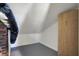 The attic space features brick wall, sloped ceiling, grey floor, and closet for additional storage at 3484 Birchwood Ave, Indianapolis, IN 46205