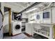 This basement laundry room features modern washer/dryer, utility sink, shelving, and natural light at 3484 Birchwood Ave, Indianapolis, IN 46205