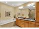 Bright bathroom with double sinks, a bathtub, granite countertops, and wood cabinets at 435 Virginia Ave # 402, Indianapolis, IN 46203