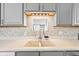 Well-lit kitchen sink with tile backsplash, window and gray cabinets at 448 Yorktown Ln, Avon, IN 46123
