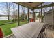 Inviting screened porch with a wooden dining table overlooking the lush green backyard and lake at 4561 Coles Dr, Columbus, IN 47201