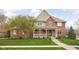 Charming brick home featuring a covered porch, well-manicured lawn, and beautiful landscaping at 4777 Madras Ct, Zionsville, IN 46077
