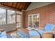Cozy screened patio featuring brick walls, wood floors, and comfortable wicker furniture with blue cushions at 4777 Madras Ct, Zionsville, IN 46077