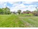A spacious, green backyard with a gravel driveway, lush grass, and mature trees; perfect for outdoor activities at 5301 Old Smith Valley Rd, Greenwood, IN 46143