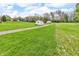 A large, grassy backyard includes a gravel driveway, a shed, and mature trees, perfect for outdoor activities at 5301 Old Smith Valley Rd, Greenwood, IN 46143