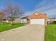 Well-maintained home with a brick accent, a spacious driveway, and a vibrant green lawn at 6233 Boulder Dr, Anderson, IN 46013