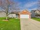 Charming single-story home featuring a brick facade, attached garage, and well-maintained lawn at 6233 Boulder Dr, Anderson, IN 46013