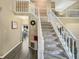 Elegant staircase with carpet steps, white railings, and view into the dining area at 7034 Endicott Way, Indianapolis, IN 46259