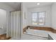Bathroom featuring white tub with tile surround and large window at 732 Trillium St, Lebanon, IN 46052