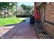 Back patio view with a basketball hoop, a play set, and a red brick house at 8808 Rocky Hill Rd, Indianapolis, IN 46217
