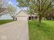 Charming home exterior features a manicured lawn, mature tree, and attached two-car garage at 936 Eagle Brook Cir, Shelbyville, IN 46176
