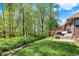 Manicured backyard with lush lawn, trees, and a wooden deck attached to a beautiful brick home at 9879 Ruby Ct, Mooresville, IN 46158