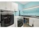 Functional laundry room with modern washer and dryer, ample cabinets, and a countertop at 9879 Ruby Ct, Mooresville, IN 46158