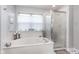 Clean bathroom featuring a soaking tub, glass-enclosed shower, and natural light at 10518 Greenway Dr, Fishers, IN 46037