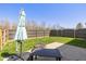 Fenced backyard with green grass, a concrete patio with table and umbrella, and a fire pit at 10876 Bellflower Ct, Indianapolis, IN 46235