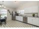 Bright kitchen featuring white cabinets, stainless steel appliances, and unique black and white patterned flooring at 10876 Bellflower Ct, Indianapolis, IN 46235