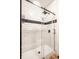 White tiled shower stall with black hardware, a black shower head, and a sliding glass door at 1603 E Market St, Indianapolis, IN 46201