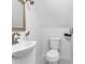 Cozy bathroom with a pedestal sink, toilet, and shower with white and brass finishes at 1621 E 44Th St, Indianapolis, IN 46205