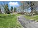 Single-story home with manicured lawn, stone facade, and circular driveway, nestled among mature trees at 1750 W Stop 11 Rd, Indianapolis, IN 46217