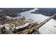 Scenic aerial view showcases the partially frozen lake, bridge, nearby condos, and surrounding wooded landscape at 20971 Shoreline Ct # 214, Noblesville, IN 46062