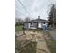 Exterior view of the back of the house with a cracked concrete patio and various items around at 2124 W 64Th St, Indianapolis, IN 46260